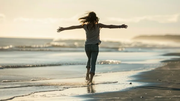 Woman running along a beautiful beach with her arms outstretched